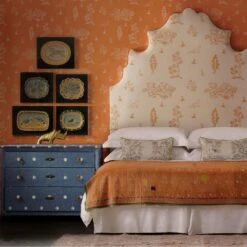 Wychwood Melon Orange Wallpaper -Andrew Martin Sale Store 339800 lucifer headboard upholstered in friendly folk melon orange fabric against wychwood melon orange wallpaper with chest of drawers in over the moon denim fabric 2200